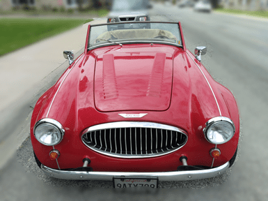 A classic red convertible sports car parked on a street.