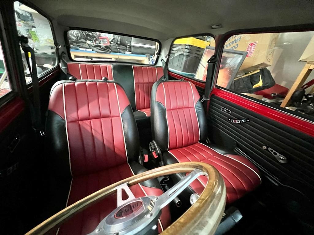 Interior of a classic car with red leather seats and a wooden steering wheel.