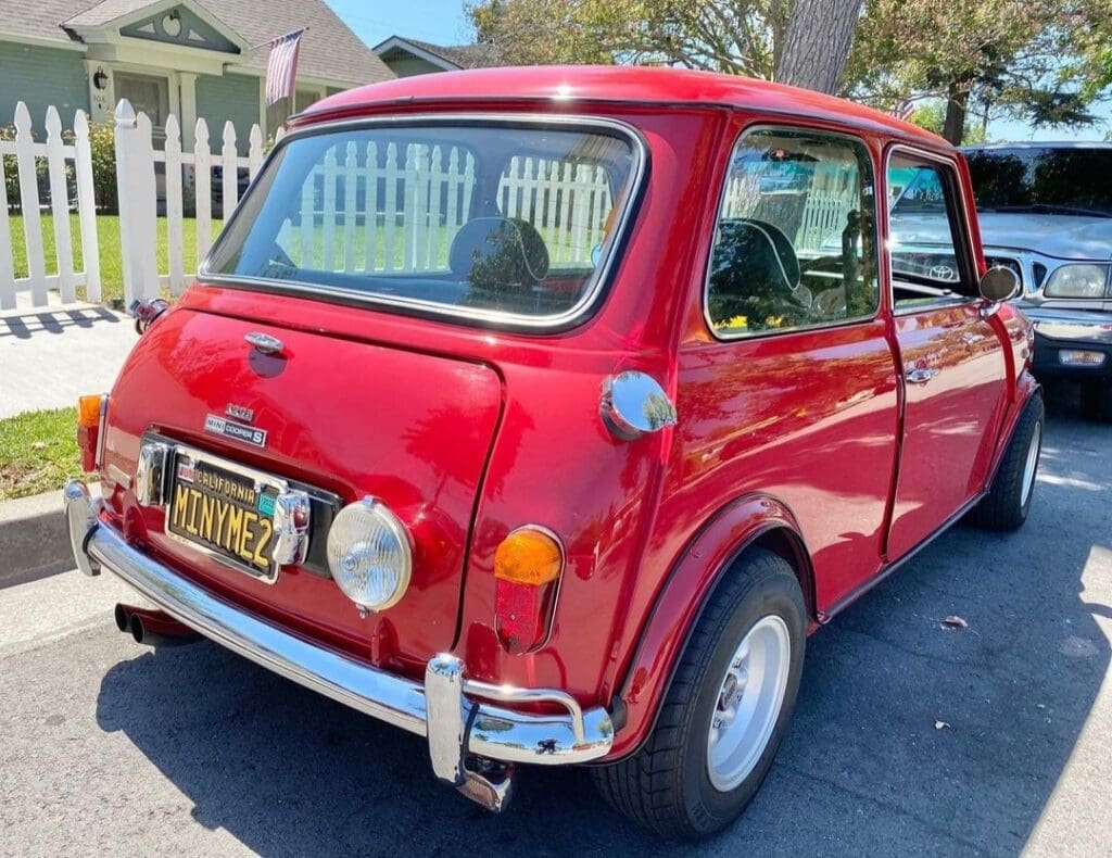 Classic red vintage Mini Cooper parked on a sunny street.