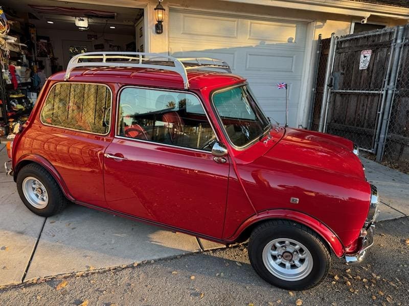 Classic red Mini Cooper parked outside a garage.