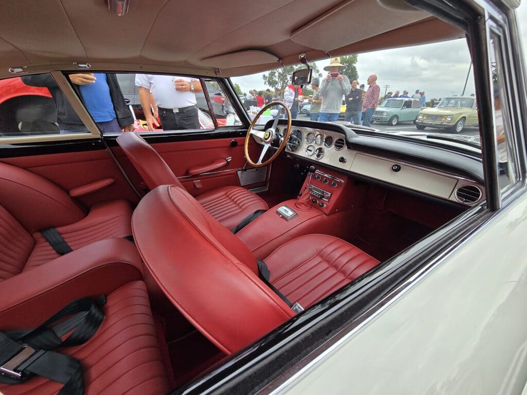 Classic car interior with red leather seats and vintage dashboard.