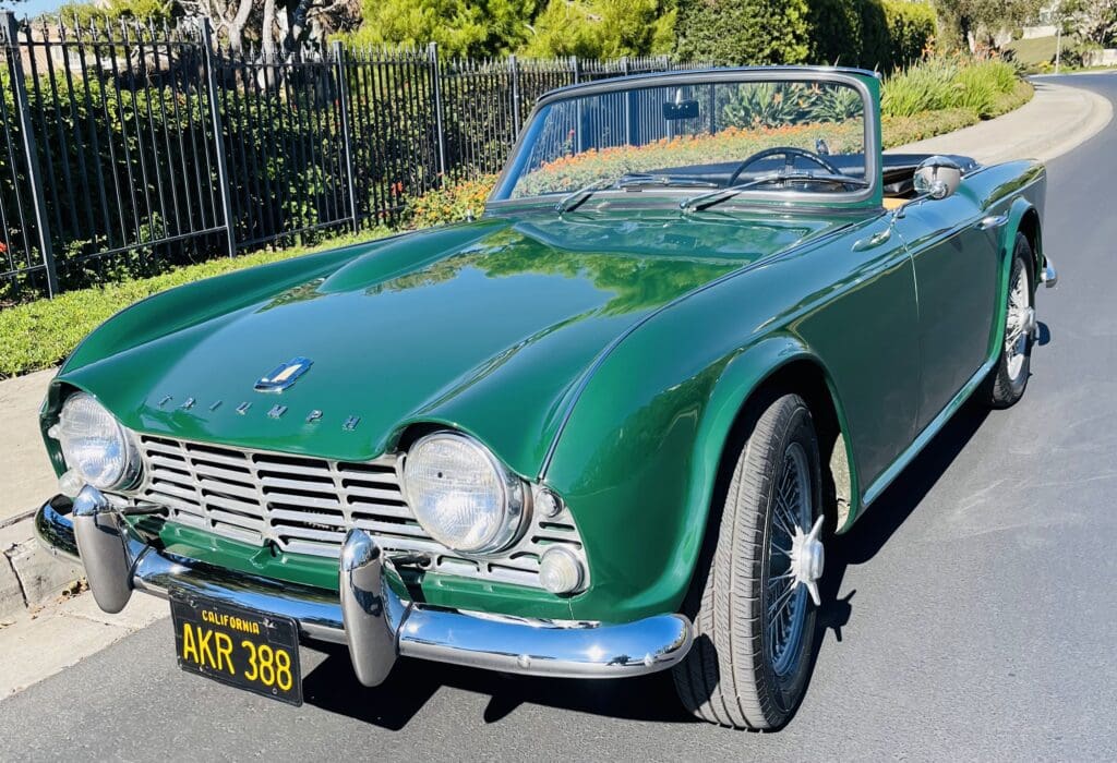 Classic green convertible car parked on a sunny day.