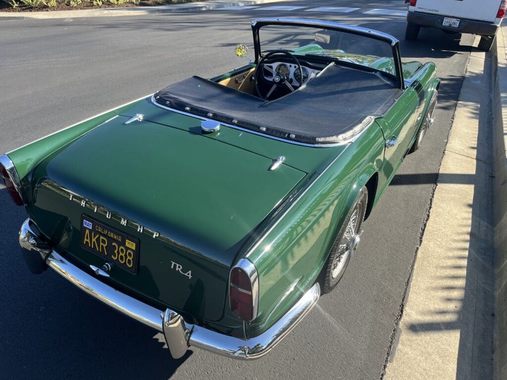 Classic green convertible car parked on the street with the top down.
