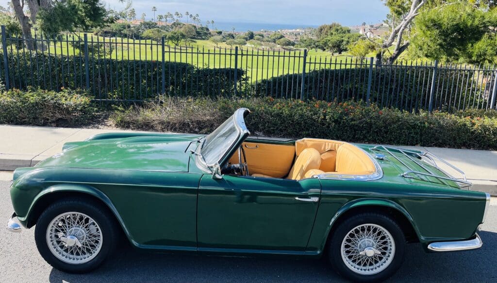 Classic green convertible car with a tan interior parked outdoors.