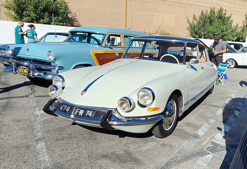 Classic white vintage car parked alongside other classic cars.