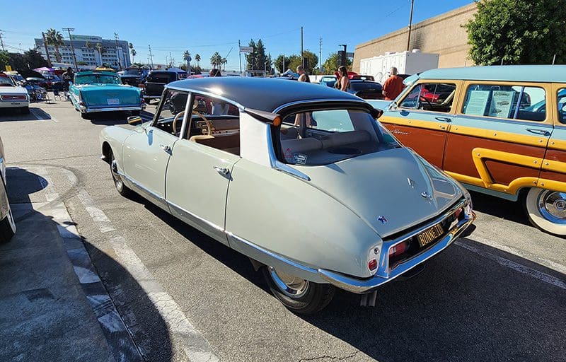 Classic white and black vintage car parked outdoors at a car show.