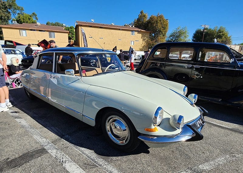 A classic white vintage car parked under a clear blue sky.