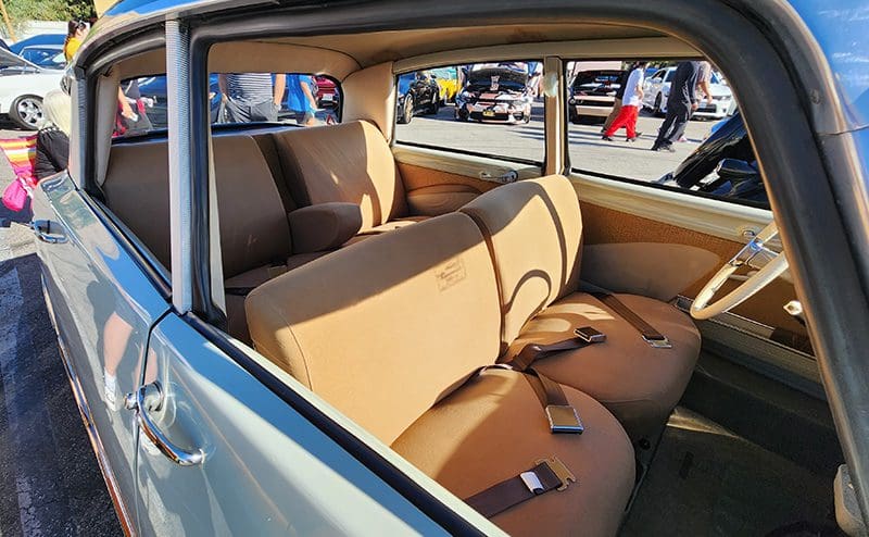 Interior of a vintage car with beige upholstery and bench seats.
