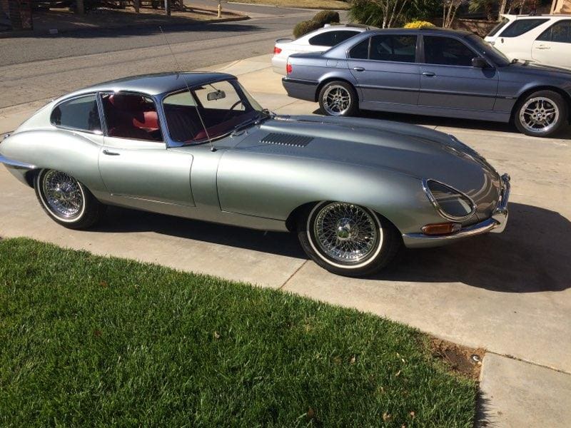 Classic silver convertible car parked on a driveway in daylight.