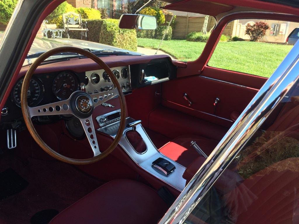 Interior of a classic red sports car with vintage steering wheel and dashboard.
