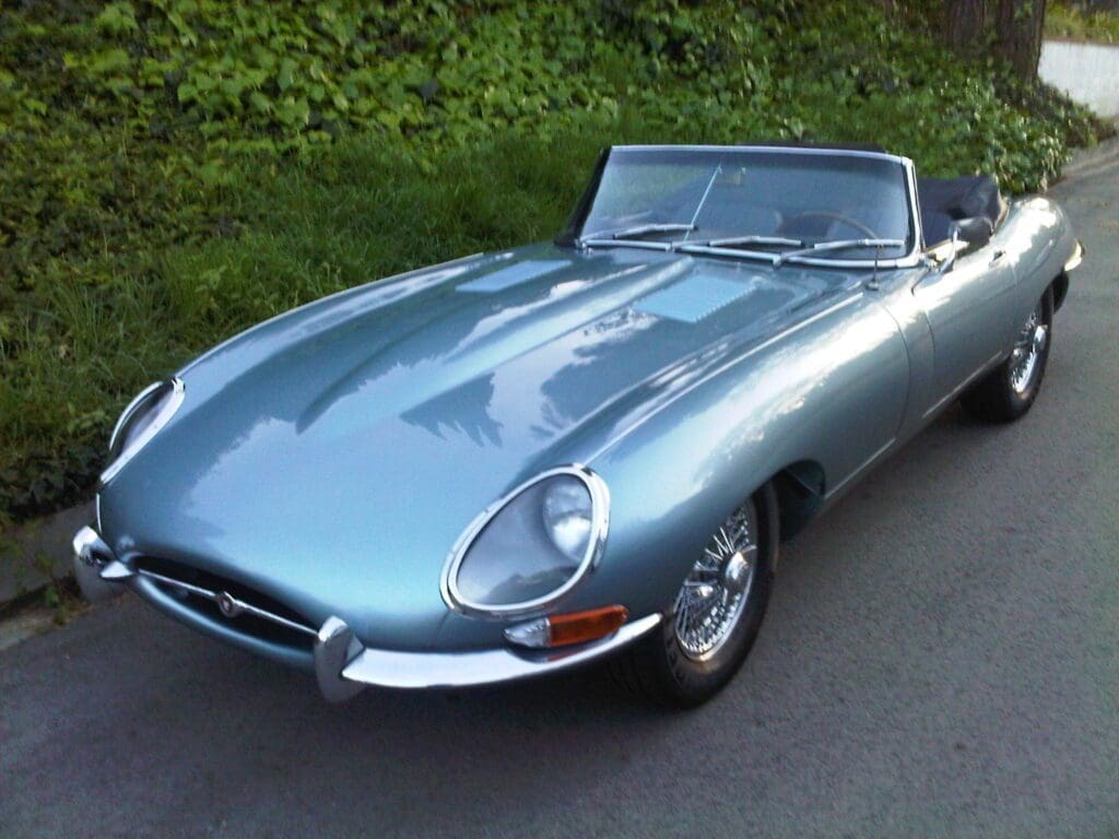 Classic silver Jaguar E-Type convertible parked outdoors.