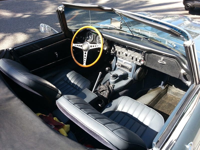 Interior of a vintage car with a wooden steering wheel and classic dashboard.