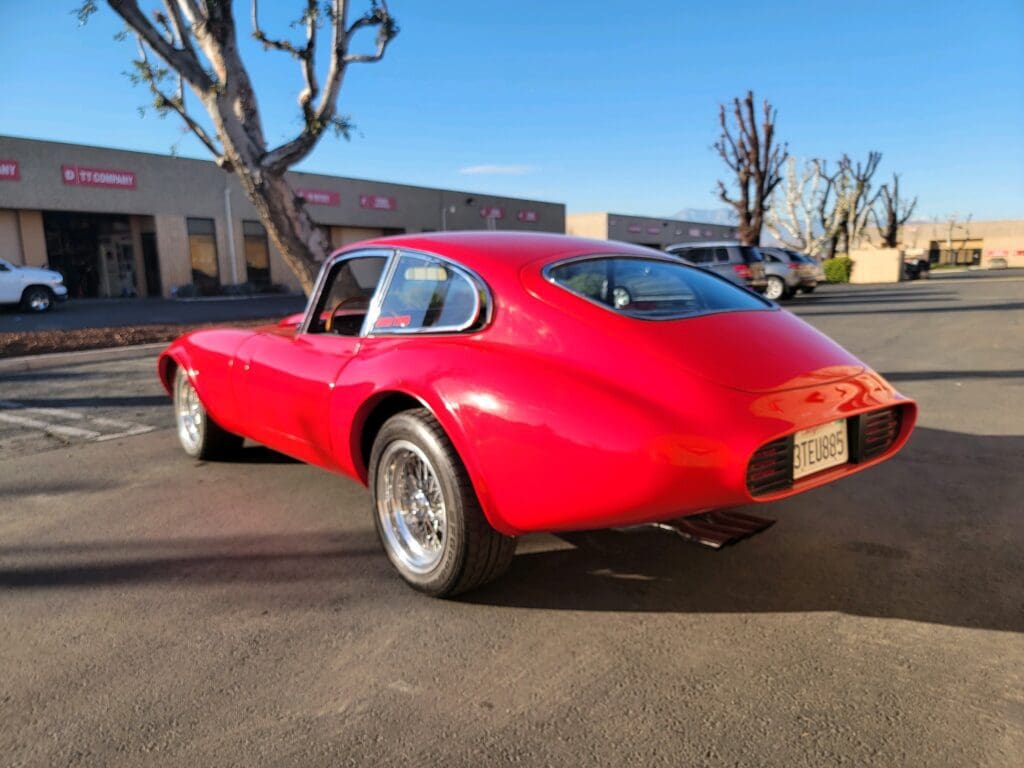 Red classic sports car parked outside on a sunny day.