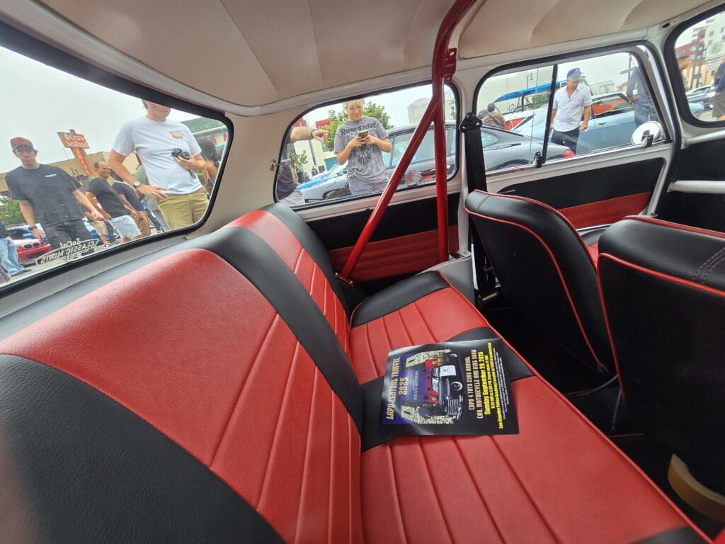 Red and black car interior with a booklet on the back seat.
