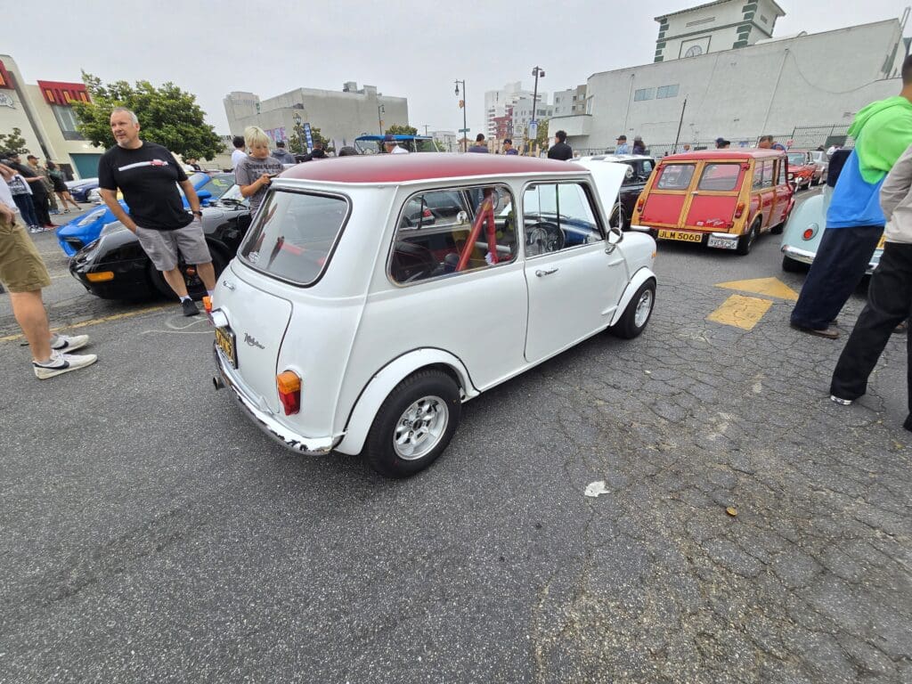 Classic white Mini Cooper with a red roof at a car gathering.