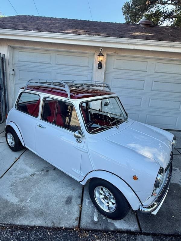 Classic white Mini Cooper parked in a driveway.