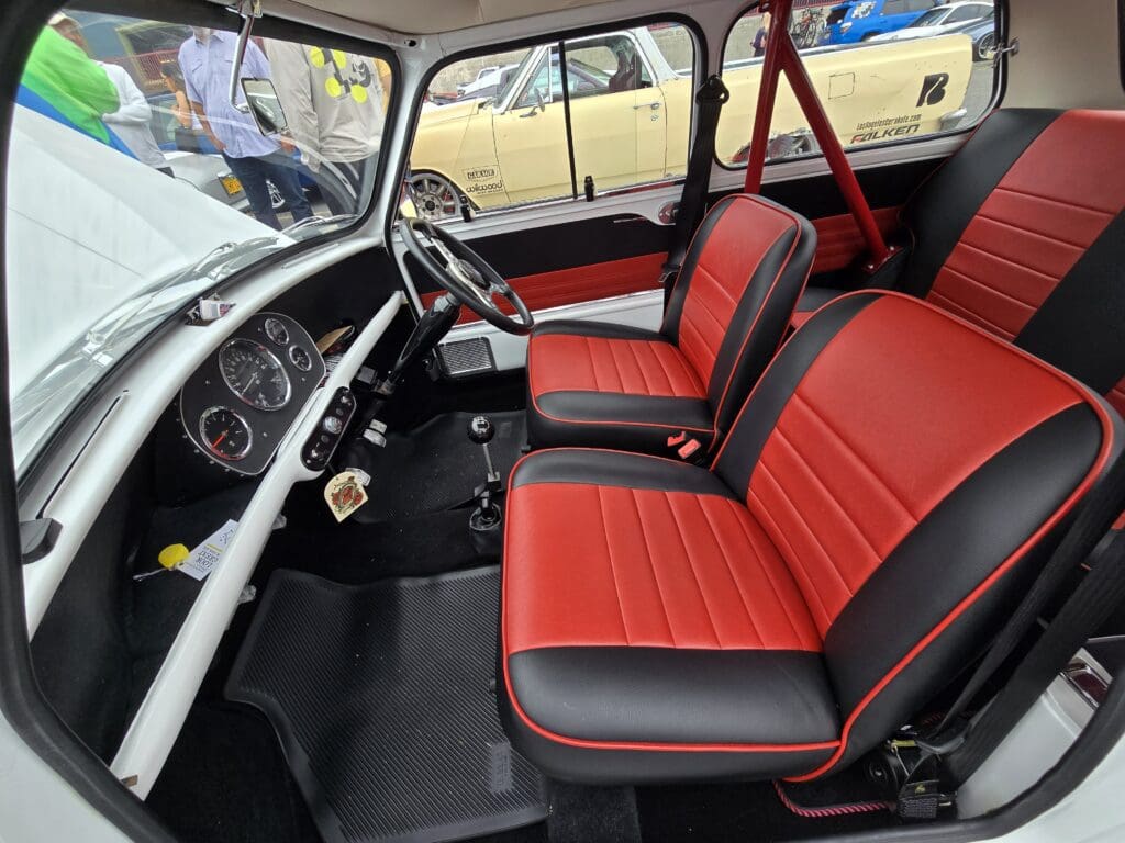 Classic car interior with red and black seats and vintage dashboard.