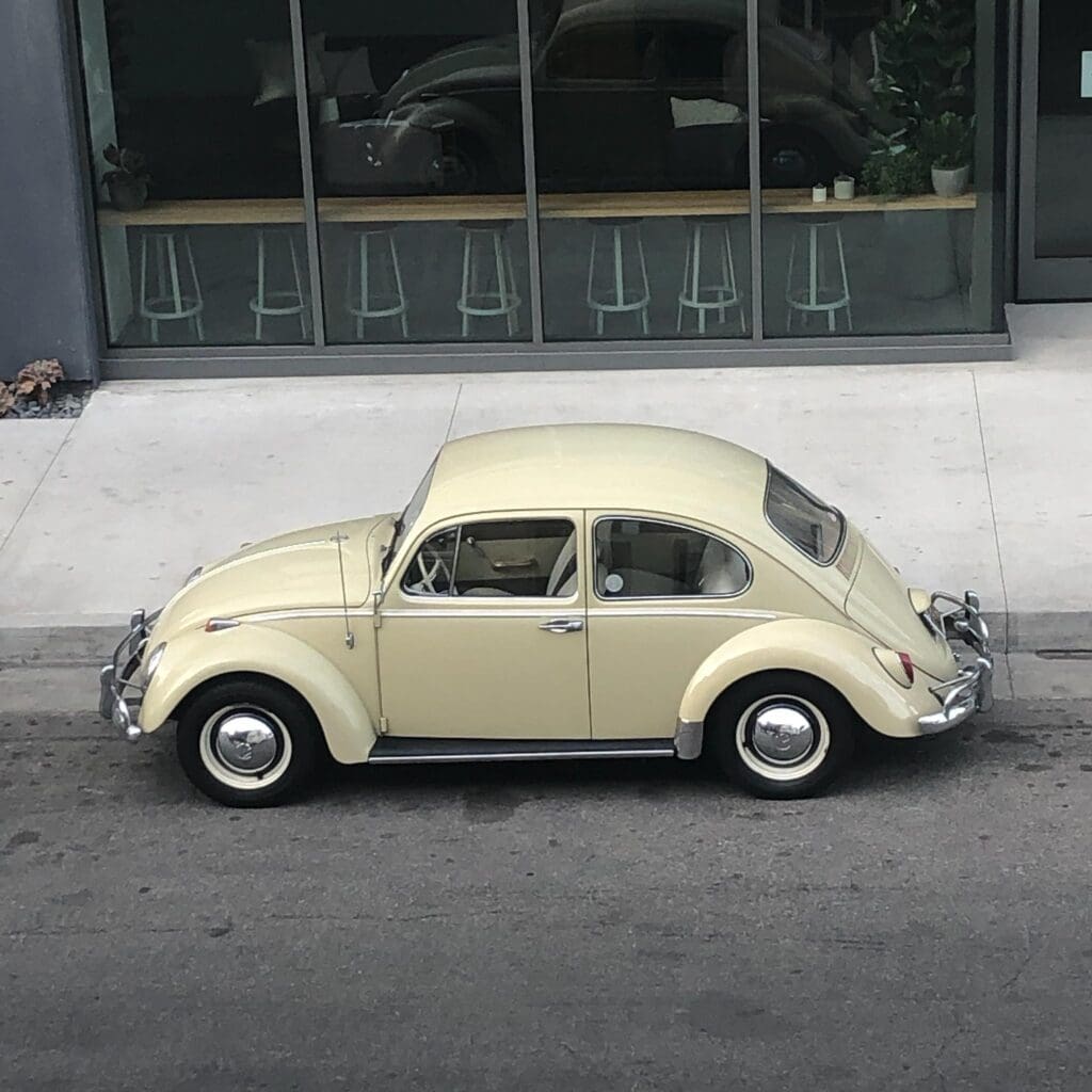 Classic beige Volkswagen Beetle parked on a city street.