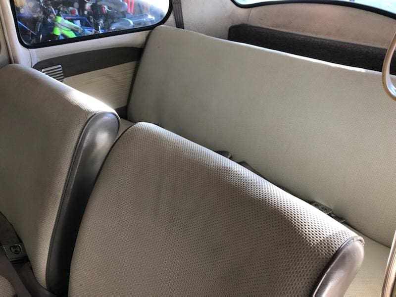 Vintage car interior with beige leather seats and classic design.