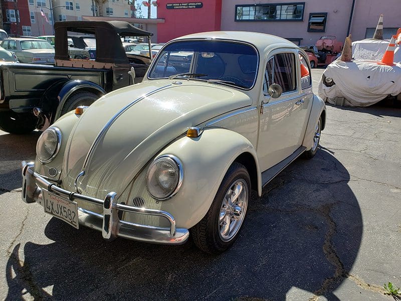 Classic beige Volkswagen Beetle parked outdoors on a sunny day.