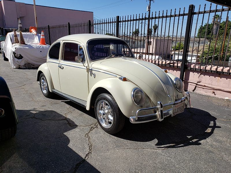 Classic cream-colored Volkswagen Beetle parked outdoors on a sunny day.