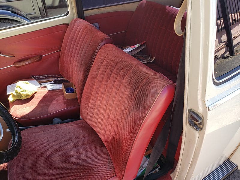 Vintage car interior with red fabric seats and classic door design.
