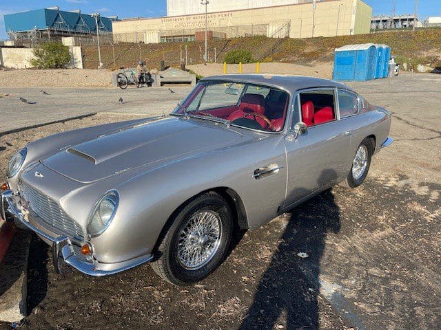Classic silver sports car with red interior parked outdoors.