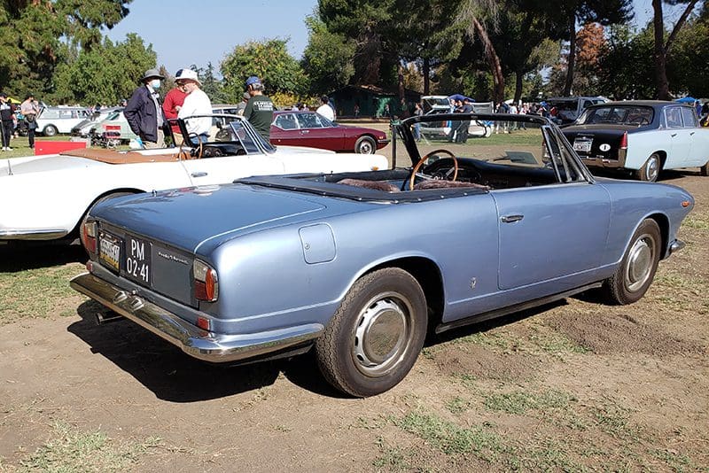 Classic light blue convertible car parked outdoors on grass.