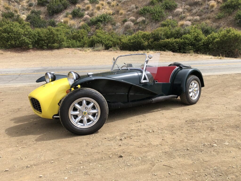 Classic black and yellow vintage roadster parked on a dirt path.