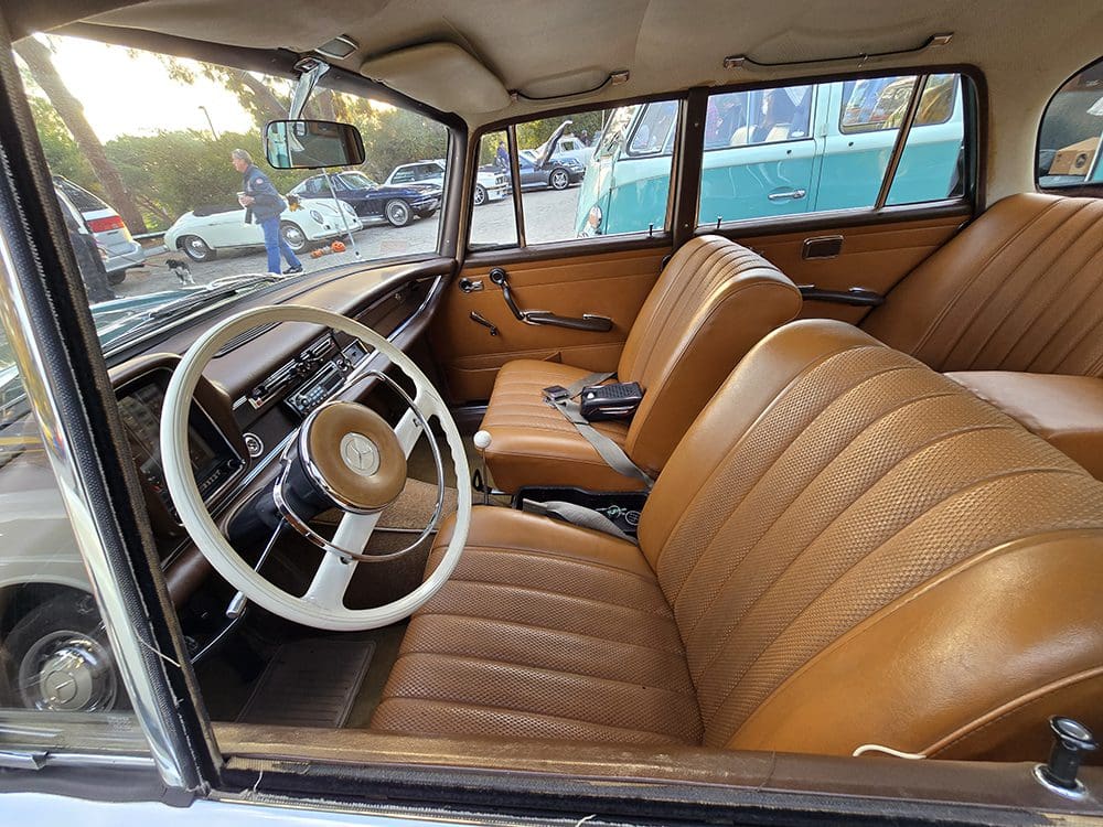Vintage car interior with tan leather seats and classic steering wheel.