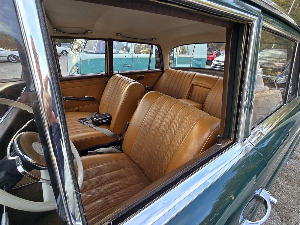 Interior of a vintage car with tan leather seats and wood details.