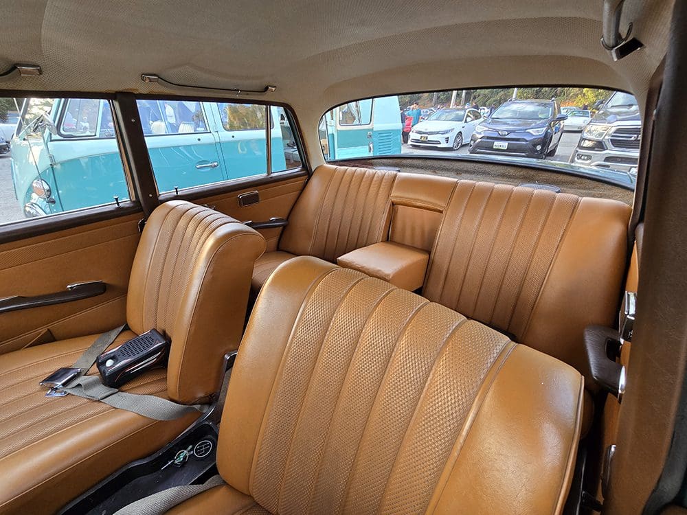 Interior view of a classic car with tan leather seats and spacious seating.