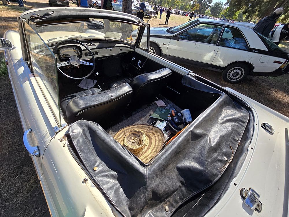 Classic convertible car with a cluttered interior and a coiled rope on the seat.
