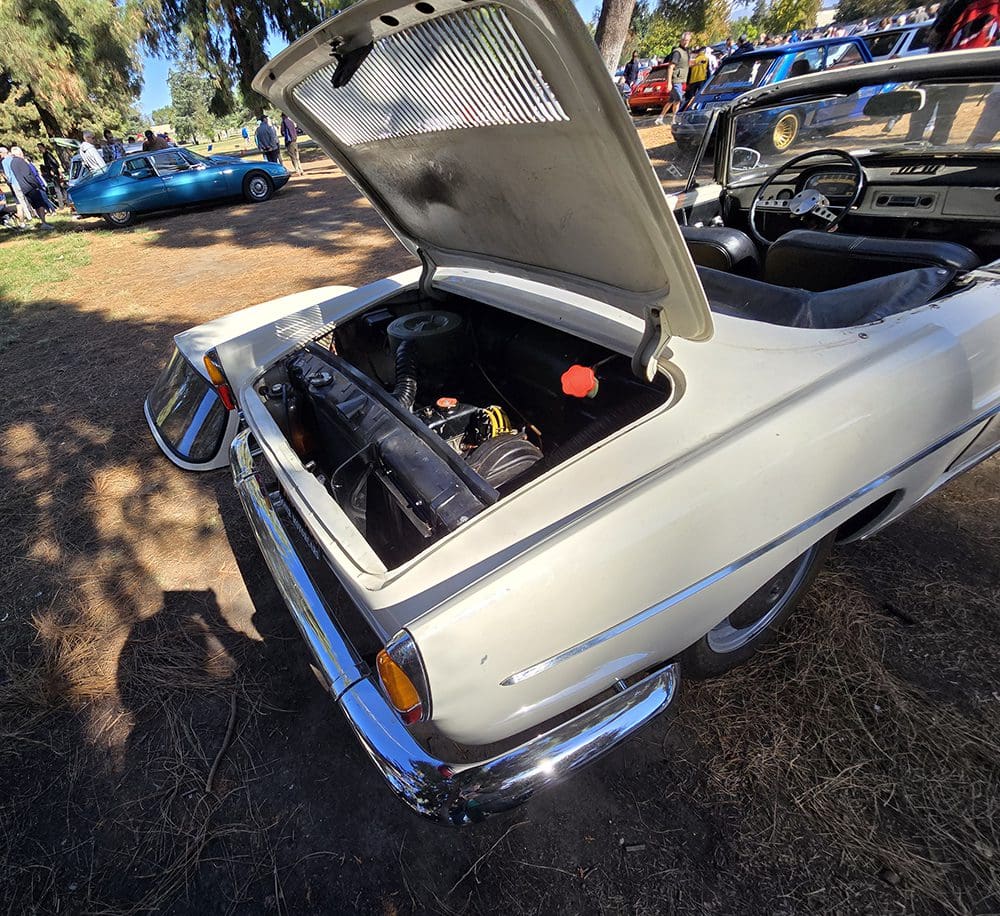 Classic white convertible car with its hood open, showing the engine.