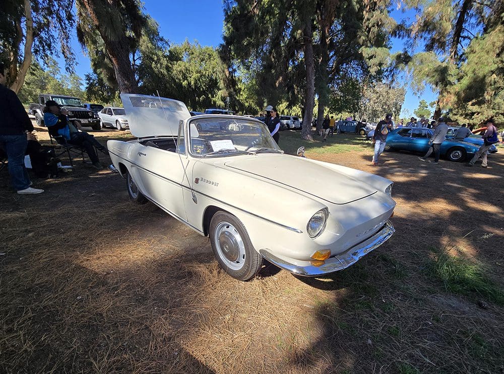 A vintage white car with gull-wing doors open at an outdoor event.