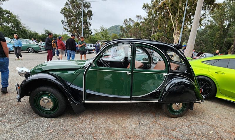 Vintage green and black Citro&euml;n 2CV car parked outdoors at a classic car event.