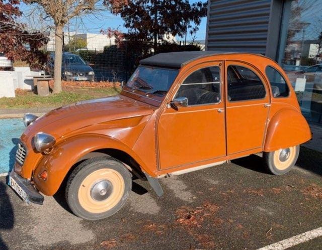 Classic orange Citro&euml;n 2CV parked outside on a sunny day.