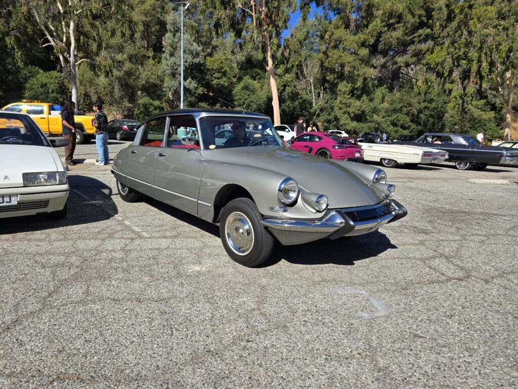 A classic silver convertible car parked outdoors on a sunny day.