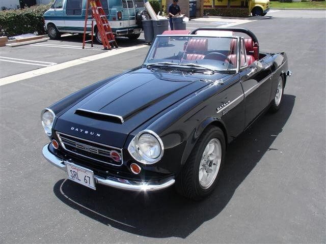 Classic black convertible sports car parked outdoors.