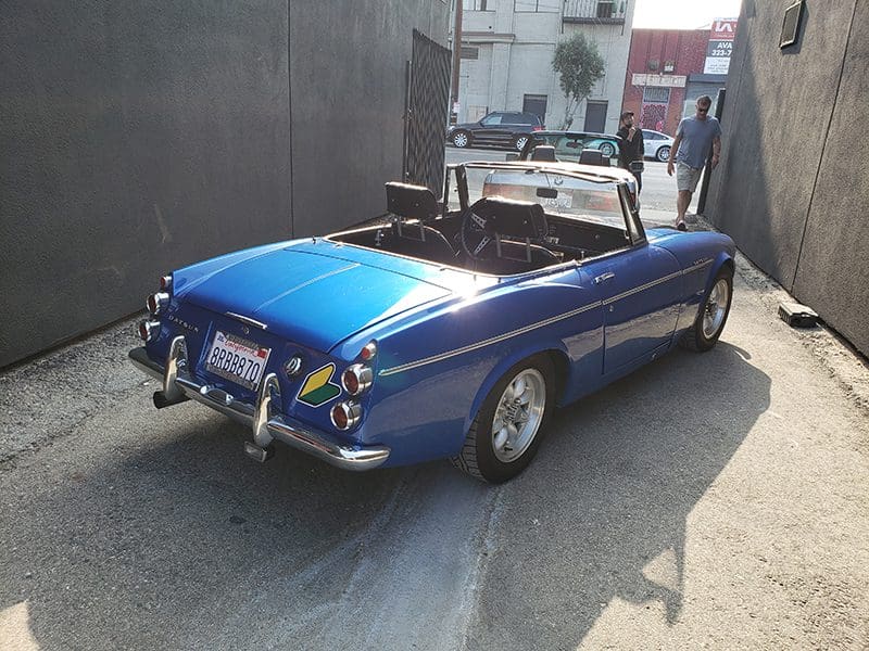 Classic blue convertible car parked on a sunny street.