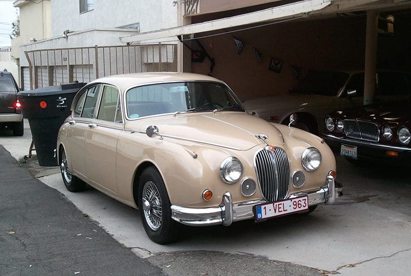 Classic beige Jaguar Mark 2 parked partially in a garage.