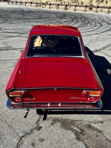 Classic red convertible car parked with mountains in the background.