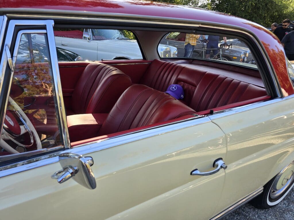 Classic car with red leather interior and partially open window.