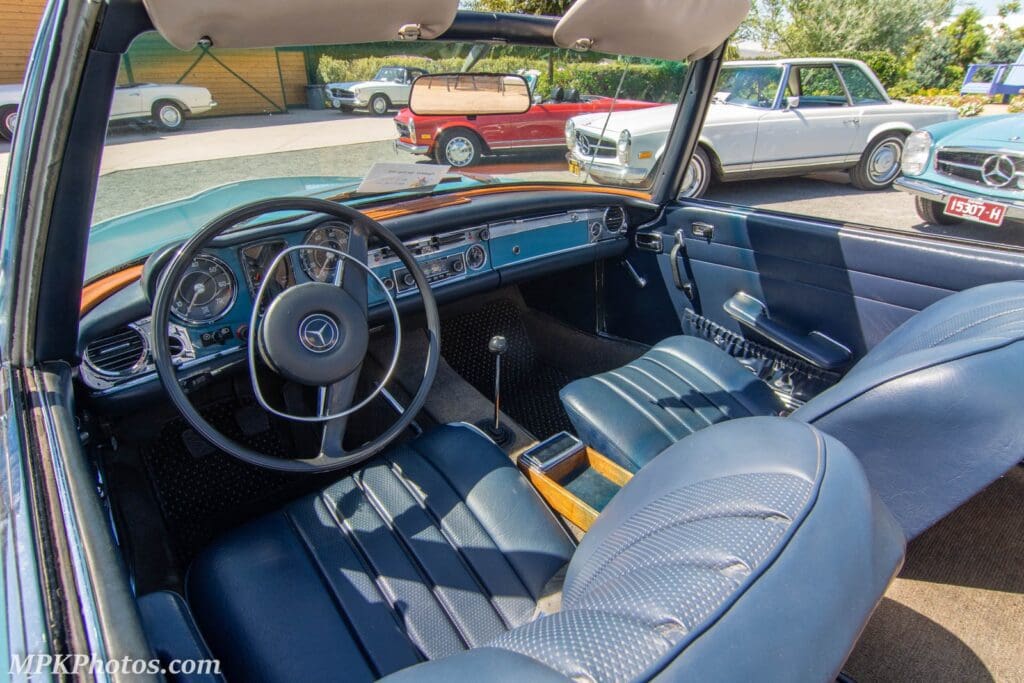 Classic car interior with blue leather seats and wooden dashboard accents.