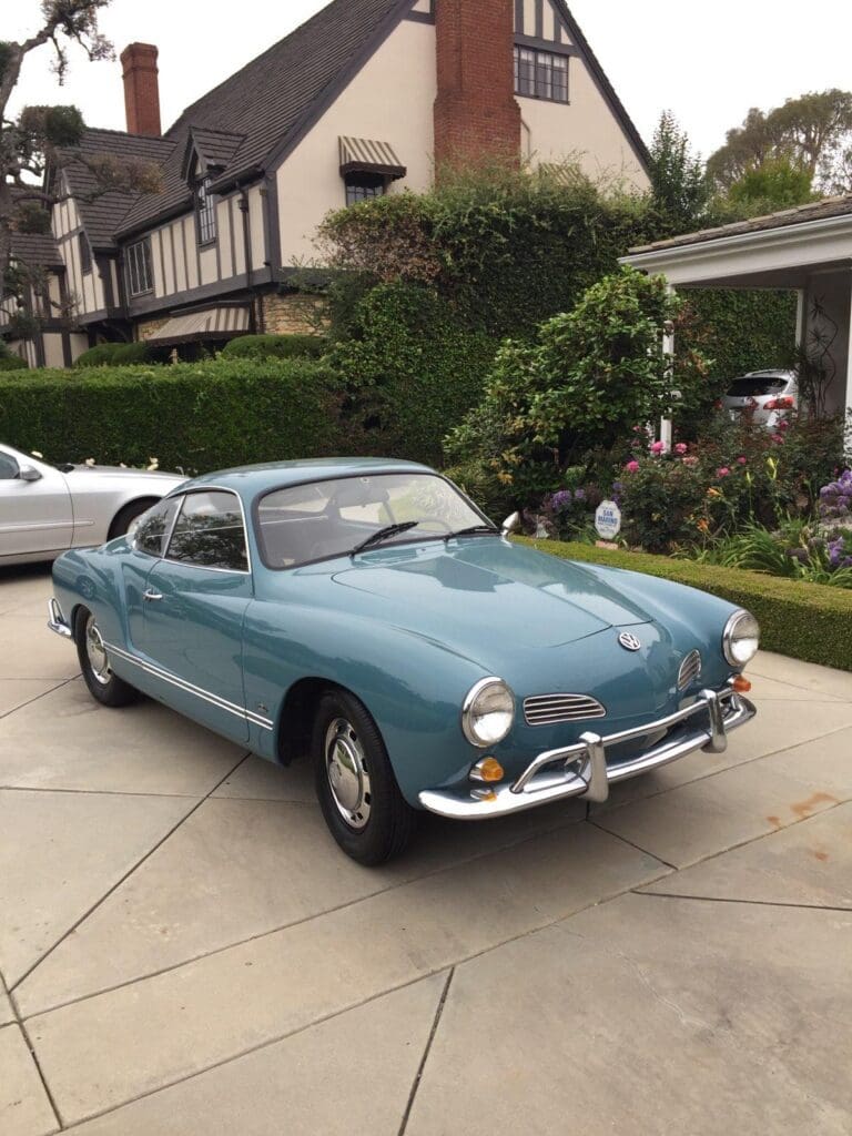 Classic light blue vintage car parked on a driveway.