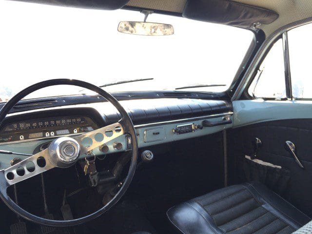 Interior view of a classic car with a vintage steering wheel and dashboard.