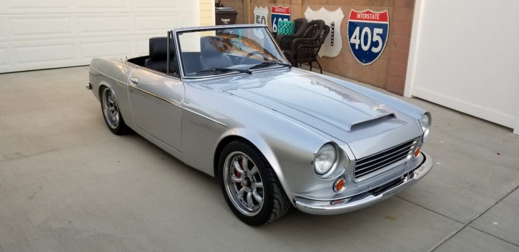 Classic silver convertible car parked indoors with vintage style.