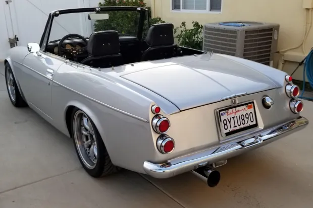 Classic silver convertible car parked indoors with vintage style.