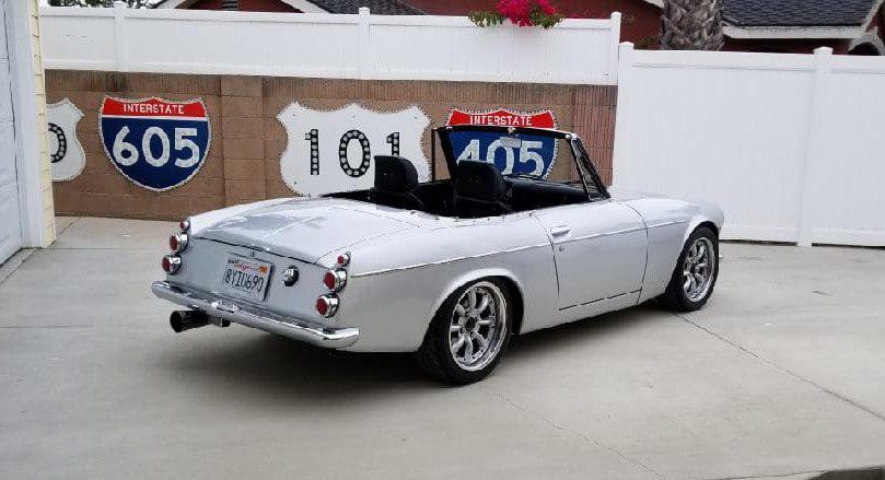 Classic white convertible car parked outdoors with a black soft top.