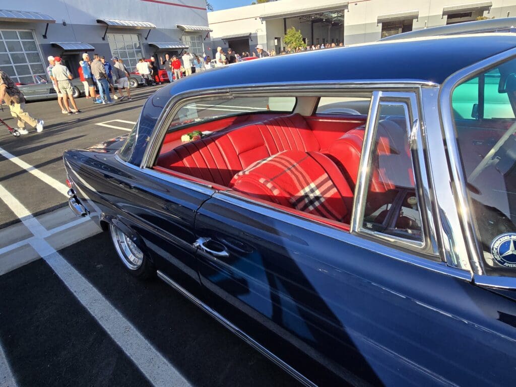 Classic car with vibrant red interior parked outdoors.